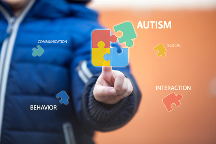 Autism Awareness Month graphic featuring a child figure with the autism symbol of puzzle pieces and related words.