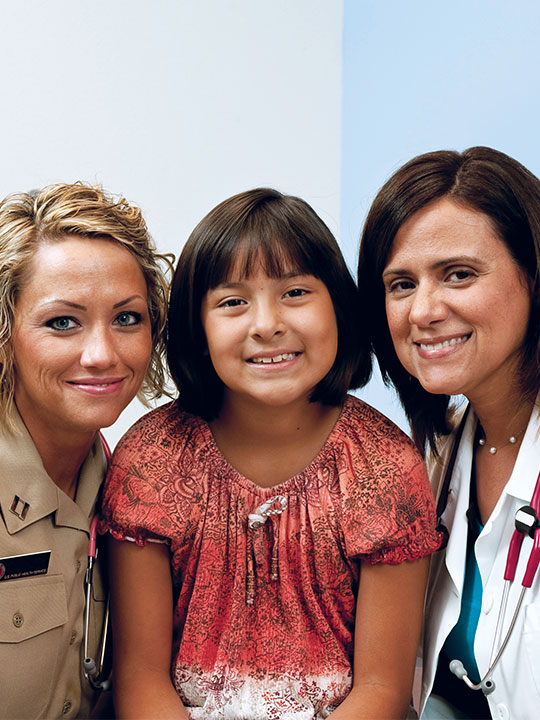 A child patient and two female medical staff smiling