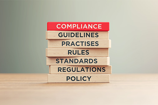 the words compliance, regulations, policy, etc. spelled out on wooden blocks