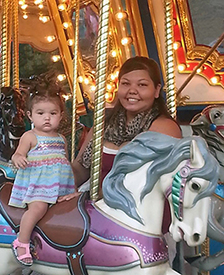 A mother and toddler daughter on a carousel