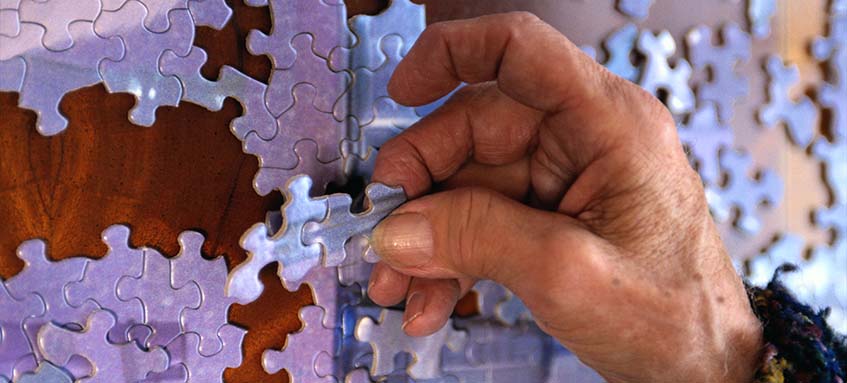 Elder hands holding puzzle pieces