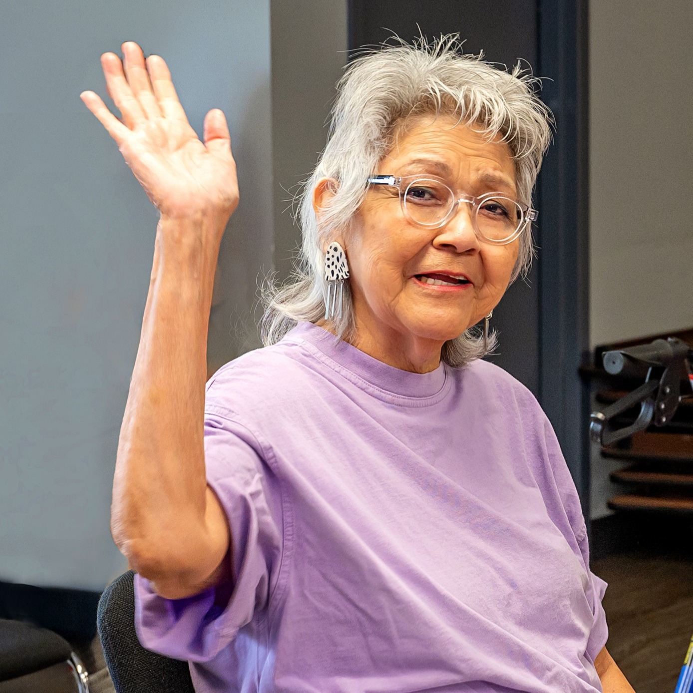 A seated elder woman waving