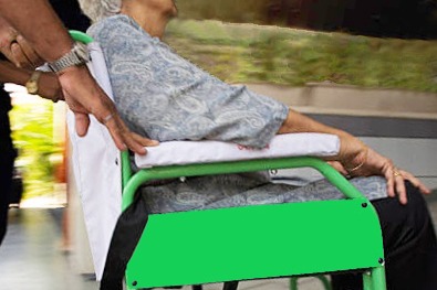 Hands pushing a wheelchair.