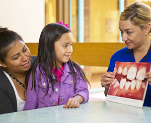 A provider showing a little girl dental information.