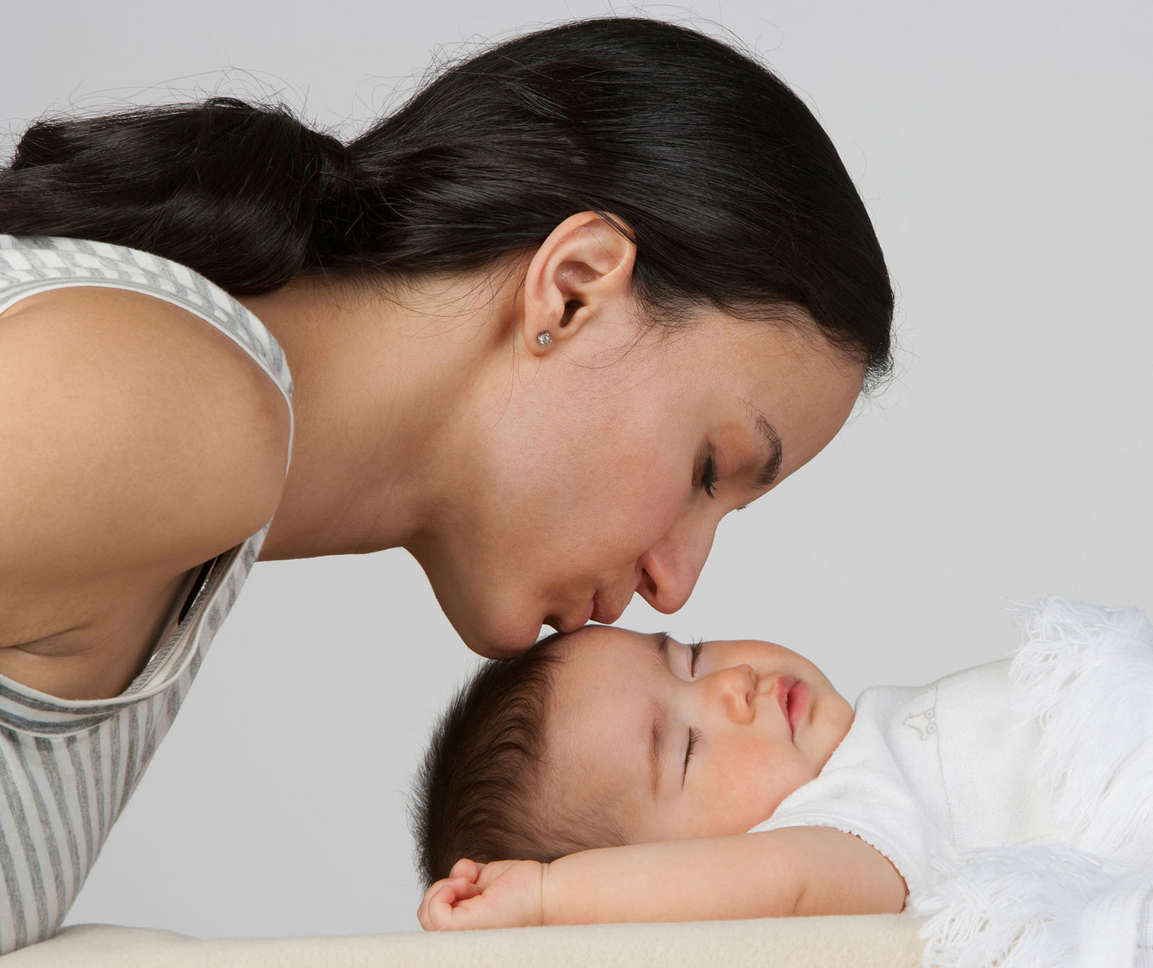 A mother kissing her sleeping baby on the forehead