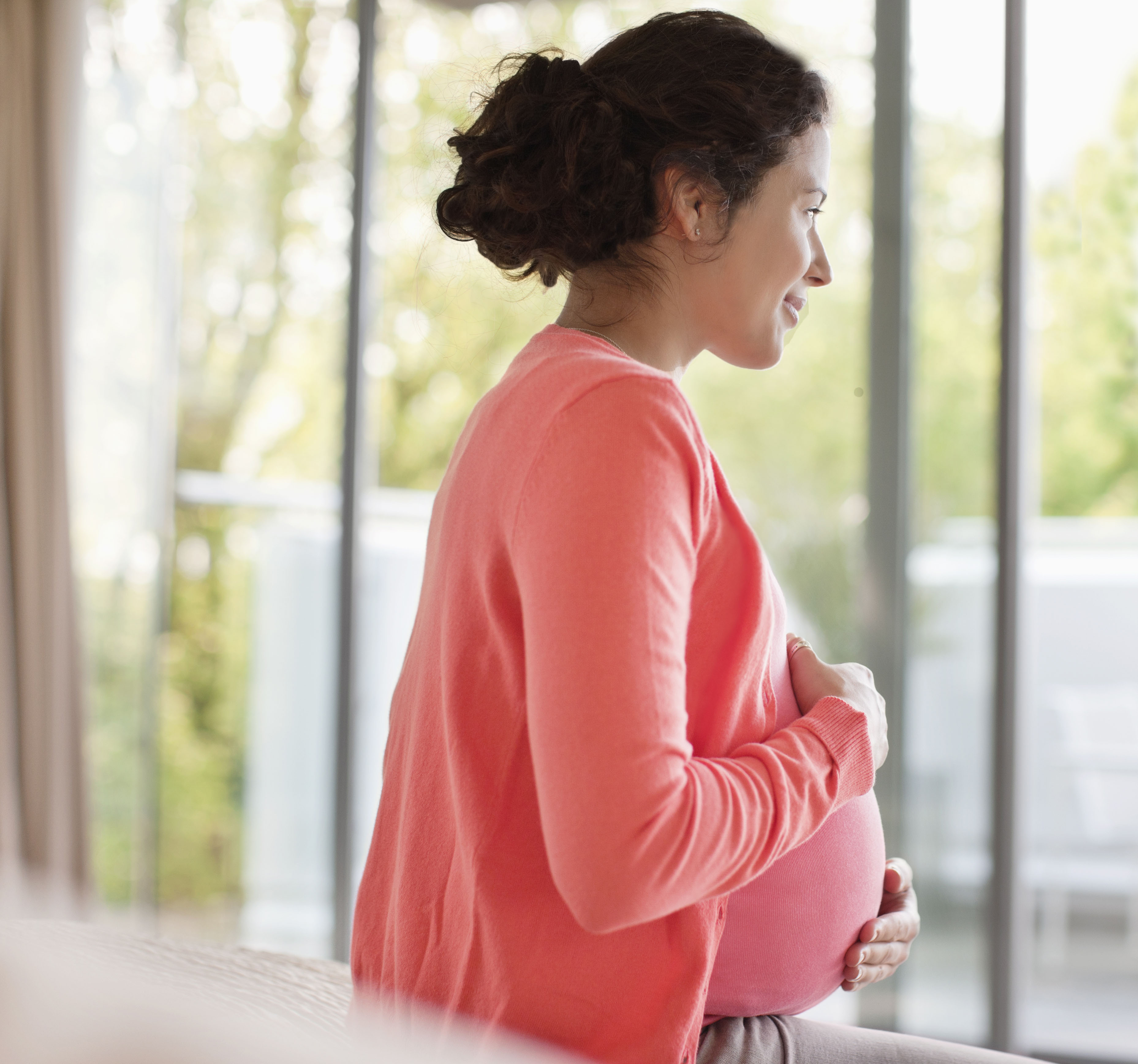 A pregnant woman looking out the window