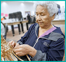 A elderly woman weaving a basket.