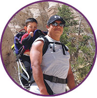 A man hiking with a child in his backpack.