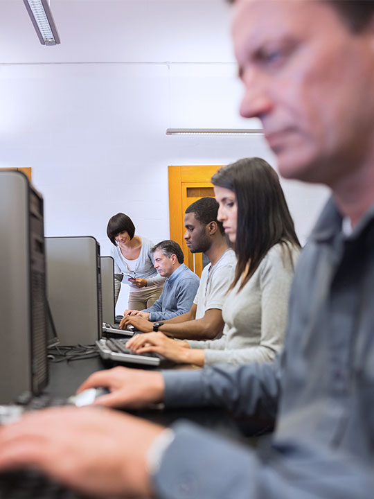 Instructor conducting training with a focus on man in front of computer