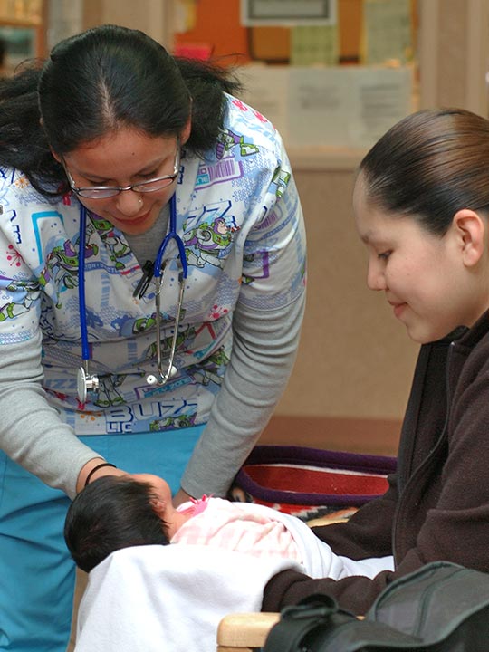 Nurse examining baby from mother's arm.