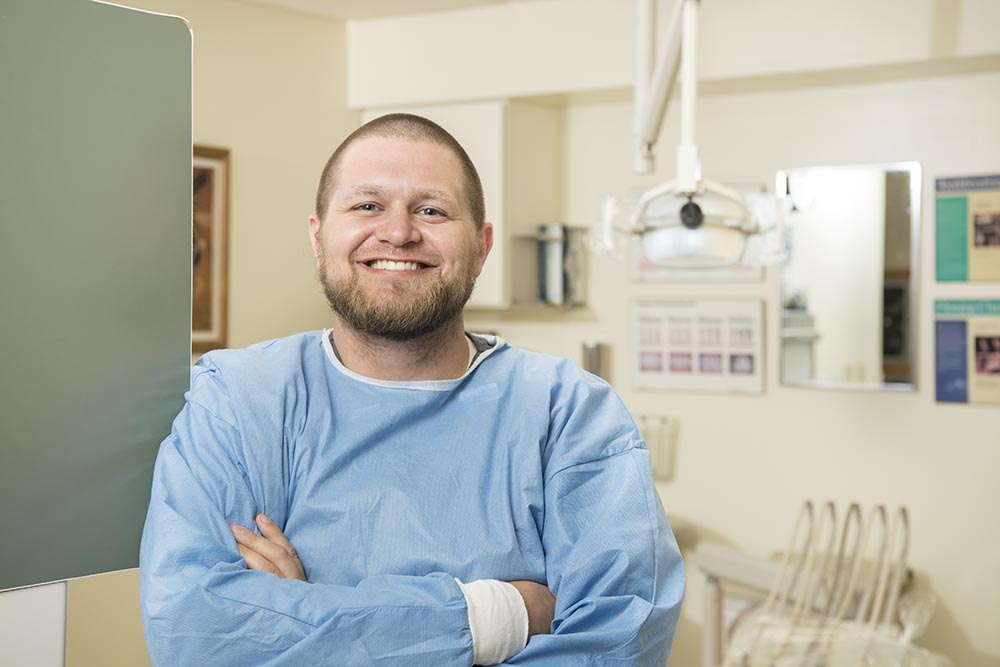 Male care provider smiles in a patient care room