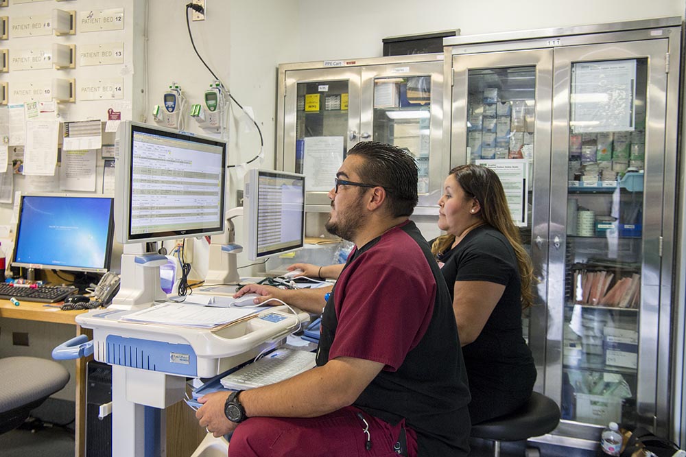 Two medical staff members sitting at a computer reviewing patient health information to deliver care to American Indian / Alaska Native patients 