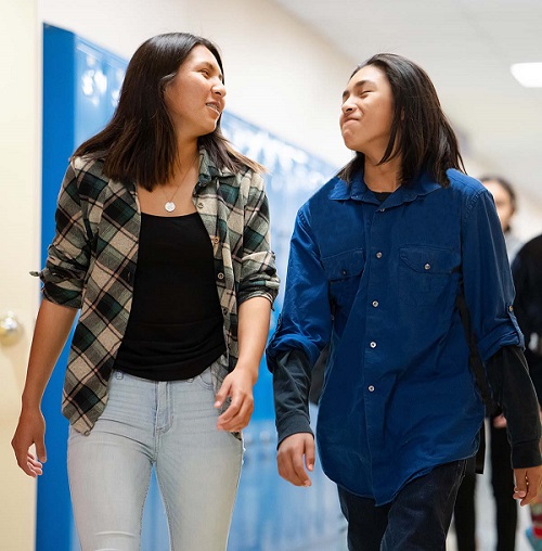 Two high schoolers walking in a hall