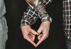 Two men making a heart shape with interlocked hands