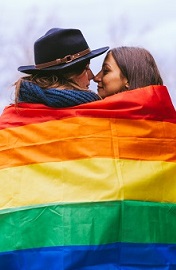 Two women wrapped in a rainbow flag
