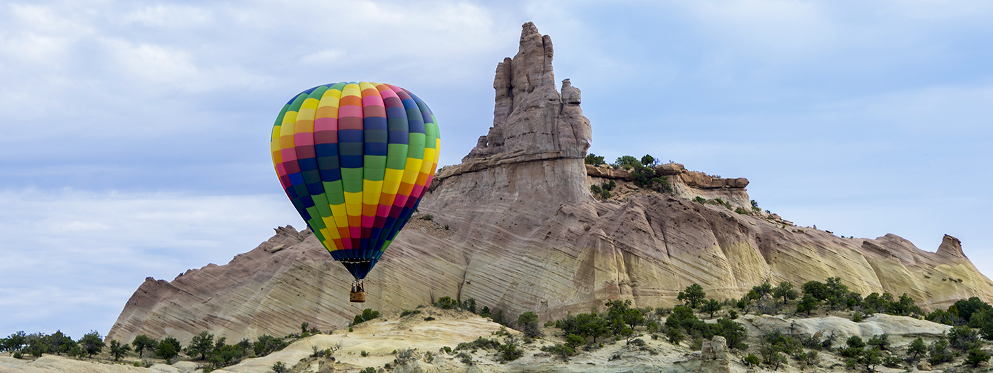 Hot air balloon rising in front of mountain