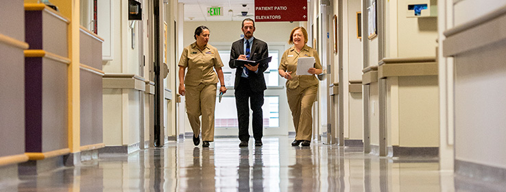 A male and two female medical staff walking.