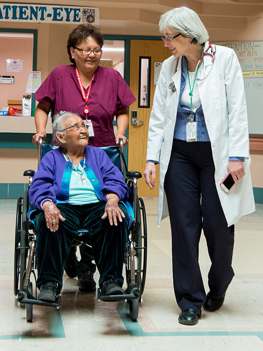 A female patient in a wheelchair with two female medical staff