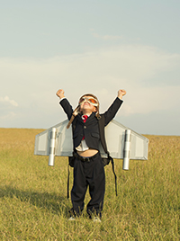 Child in field with homemade cardboard jetpack.