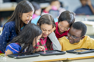 Elementary students share a tablet.