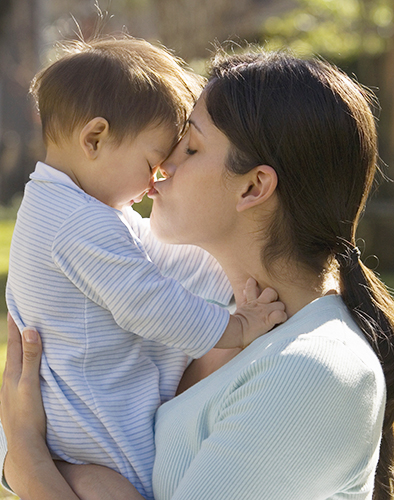 Mother holding and kissing baby