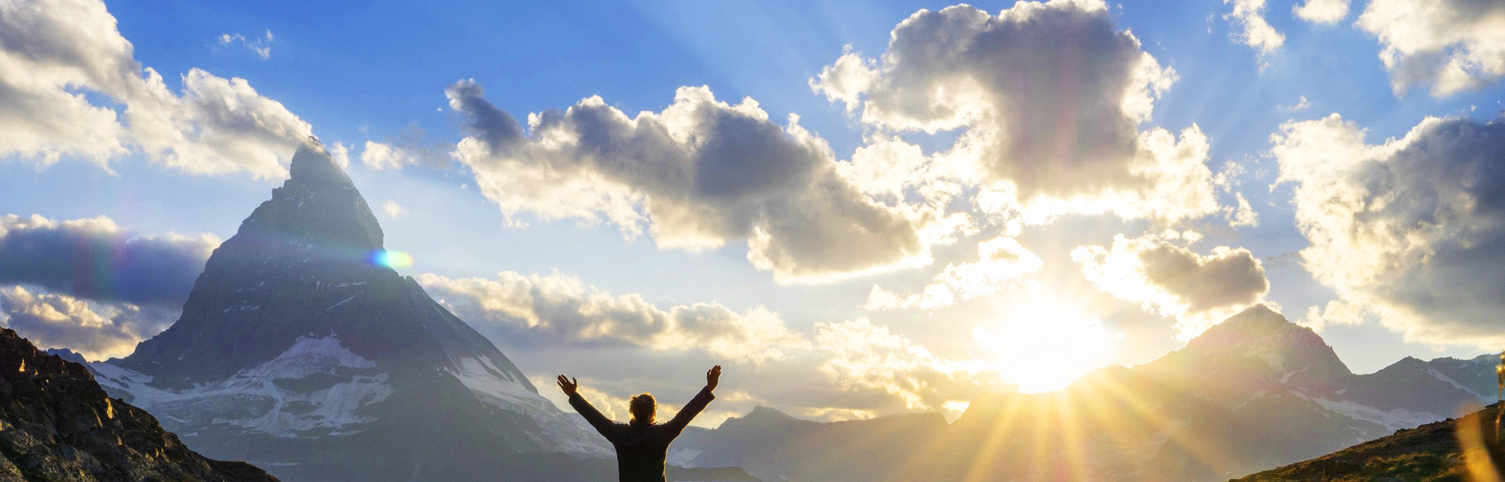 person with arms outstretched at sunrise