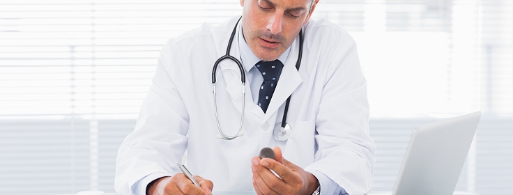 Doctor holding medication and writing a prescription