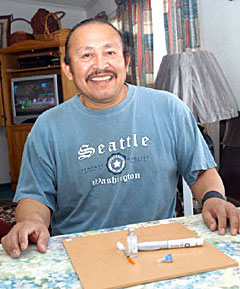 Photo of a man sitting at a table with an insulin needle, insulin bottle, and a glucose reader. Photo of a man sitting at a table with an insulin needle, insulin bottle, and a glucose reader.