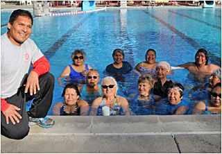 An instructor posing with his water aerobics class.