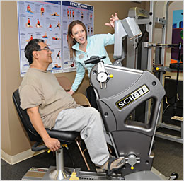 DIHFS staff member showing a client how to use exercise equipment.
