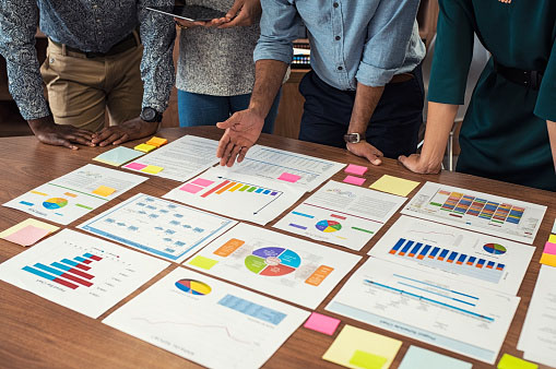 people hovering over a table with reports on it