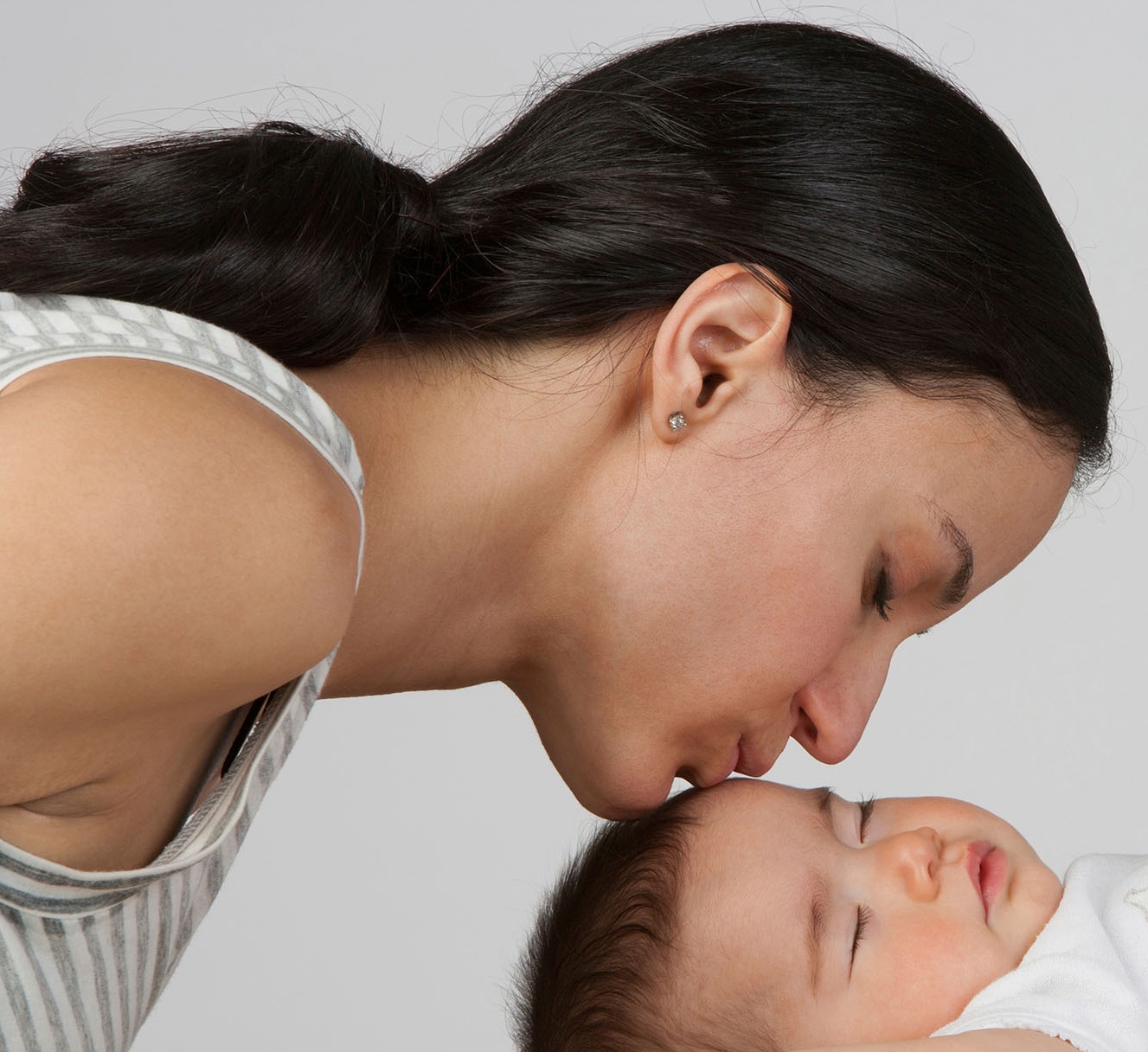 A mother kissing her sleeping baby on the forehead